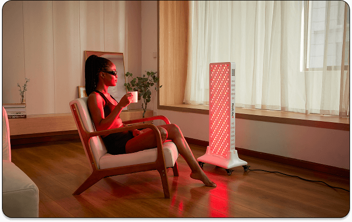 A woman sitting on a chair using an infrared lamp